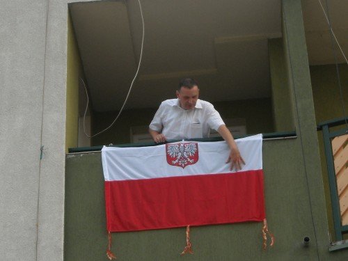Paweł Porębski wiesza flagę przed świętem Wojska Polskiego
